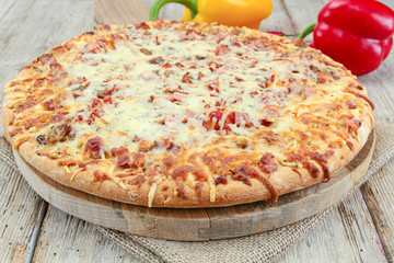 whole pizza with ham and mozzarella on a wooden table