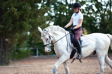 Young lady riding a trotting horse practicing at equestrian school