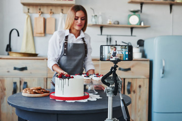 Woman makes delicious sweets and pie. Recording process by smartphone on tripod