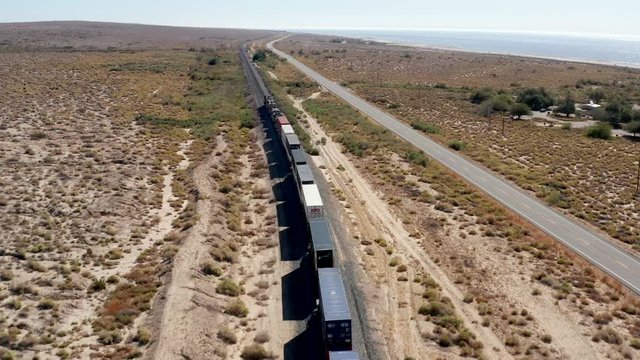 Railway With Cargo Train Moving By Road in Californian Desert, Bird Eye Tracking Aerial View