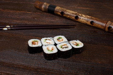 Fresh sushi roles on a wooden plate with hands of the chef in the background