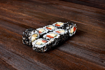 Fresh sushi roles on a wooden plate with hands of the chef in the background