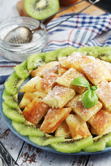 Austrian dessert Kaiserschmarrn served with sugar powder and kiwi fruit	