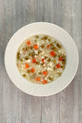 Rice soup with chicken, green peas and carrots. Directly Above.