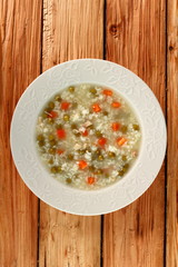 Rice soup with chicken, green peas and carrots. Directly Above.