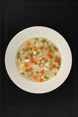 Rice soup with chicken, green peas and carrots. Directly Above.