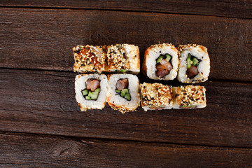 Fresh sushi roles on a wooden plate with hands of the chef in the background