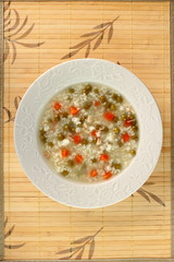 Rice soup with chicken, green peas and carrots. Directly Above.
