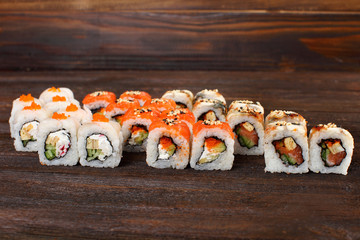 Fresh sushi roles on a wooden plate with hands of the chef in the background