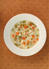 Rice soup with chicken, green peas and carrots. Directly Above.