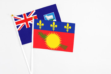 Guadeloupe and Falkland Islands stick flags on white background. High quality fabric, miniature national flag. Peaceful global concept.White floor for copy space.