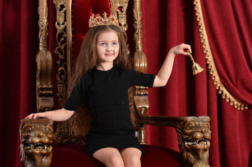 Portrait of a happy girl princess posing on throne