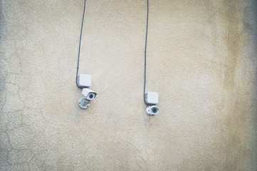 Two cctv cameras on the dirty wall of an old building. Soft focus, grunge processing.