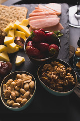 Cheese and fruits plate with glass of white wine on round tray, colorful and delicious charcuterie with snacks and wineglass for romantic evening, wine tasting, selective focus.