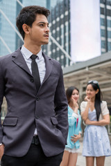 Young smart businessman and behind two girl taking gossip
