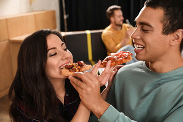 Young couple eating delicious pizza in cafe, closeup