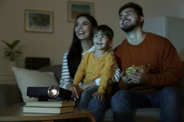 Family watching movie at home, focus on video projector