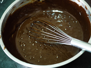Chocolate butter cream in big bowl, processing cupcakes.