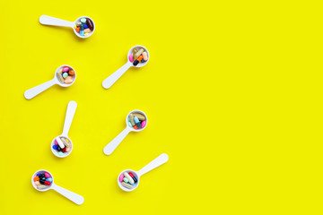Colorful tablets with capsules and pills on yellow background.
