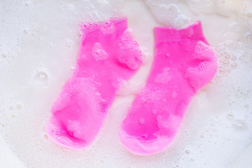 Obraz na płótnie Canvas Pink socks soaking in powder detergent water dissolution. Laundry concept.