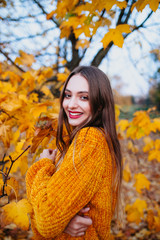 Beautiful woman with red lips in bright yellow sweater enjoying in a sunny autumn day