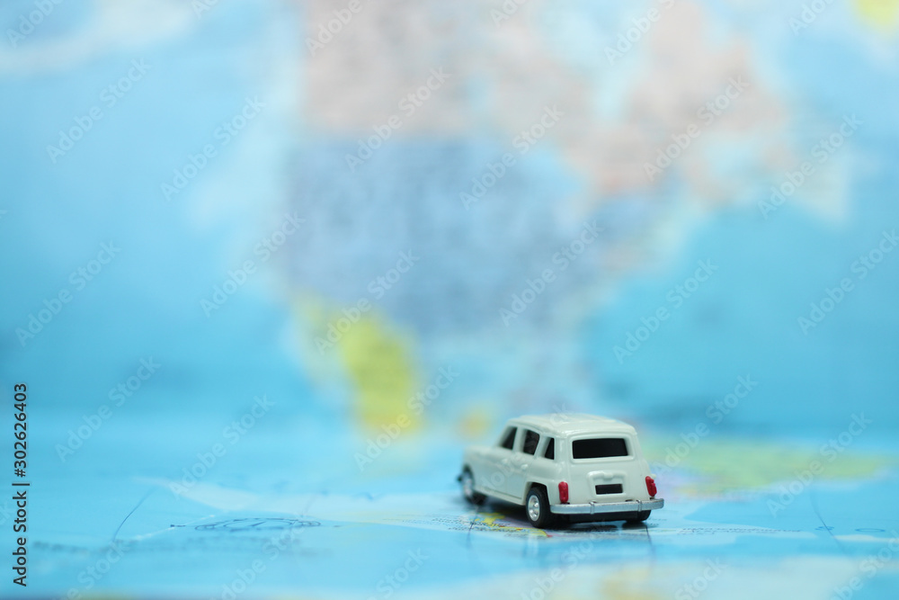 Wall mural closeup of miniature white car toy on colorful world map with copy space. using for global travel an