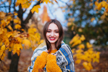 Funny girl with red lips in a warm plaid on a sunny autumn day