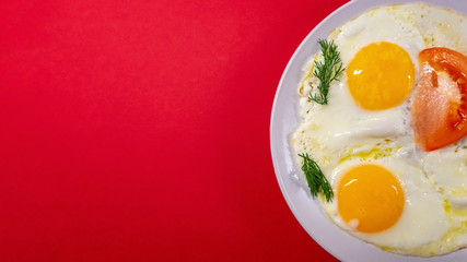 Fried eggs from two eggs close-up on a light plate, on a red background. The concept of fun food.