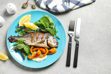 Delicious roasted fish with lemon on grey table, flat lay