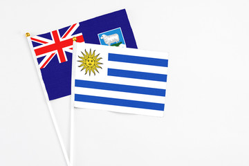 Uruguay and Falkland Islands stick flags on white background. High quality fabric, miniature national flag. Peaceful global concept.White floor for copy space.