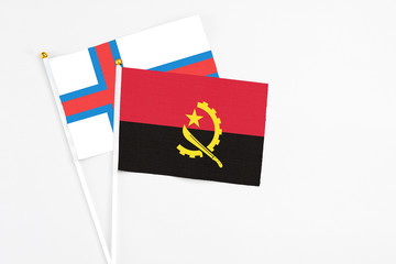 Angola and Faroe Islands stick flags on white background. High quality fabric, miniature national flag. Peaceful global concept.White floor for copy space.