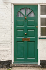 Green front door with a knob, a knocker and a mail slot