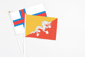 Bhutan and Faroe Islands stick flags on white background. High quality fabric, miniature national flag. Peaceful global concept.White floor for copy space.