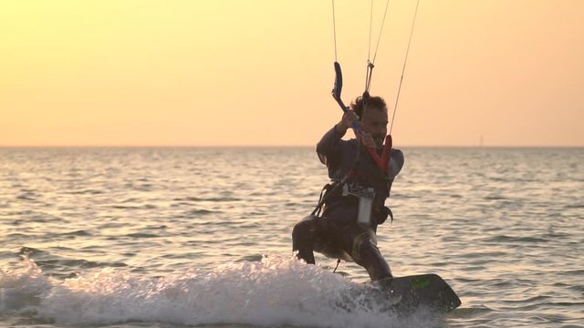 Colorful sky during sunset on the background of a kite surfer gliding on water