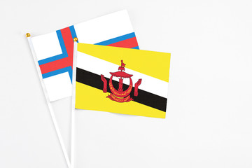 Brunei and Faroe Islands stick flags on white background. High quality fabric, miniature national flag. Peaceful global concept.White floor for copy space.