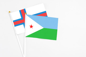 Djibouti and Faroe Islands stick flags on white background. High quality fabric, miniature national flag. Peaceful global concept.White floor for copy space.