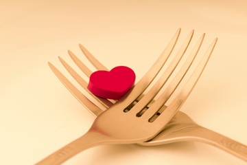Romantic dinner. Golden forks with red heart. valentine day