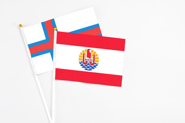 French Polynesia and Faroe Islands stick flags on white background. High quality fabric, miniature national flag. Peaceful global concept.White floor for copy space.