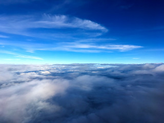 Clouds and sky as seen through window of an aircraft.Airplane wing in the blue sky above the clouds.