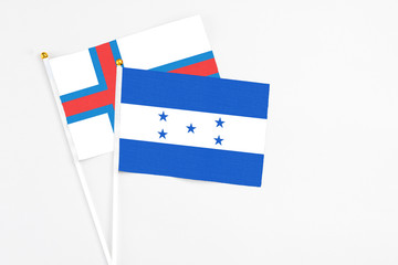 Honduras and Faroe Islands stick flags on white background. High quality fabric, miniature national flag. Peaceful global concept.White floor for copy space.