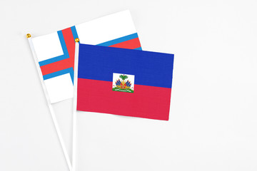 Haiti and Faroe Islands stick flags on white background. High quality fabric, miniature national flag. Peaceful global concept.White floor for copy space.