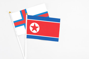 North Korea and Faroe Islands stick flags on white background. High quality fabric, miniature national flag. Peaceful global concept.White floor for copy space.