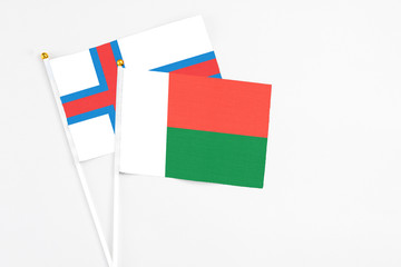 Madagascar and Faroe Islands stick flags on white background. High quality fabric, miniature national flag. Peaceful global concept.White floor for copy space.