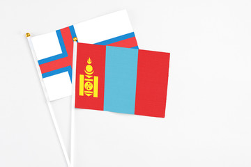 Fototapeta premium Mongolia and Faroe Islands stick flags on white background. High quality fabric, miniature national flag. Peaceful global concept.White floor for copy space.