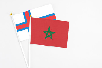 Morocco and Faroe Islands stick flags on white background. High quality fabric, miniature national flag. Peaceful global concept.White floor for copy space.