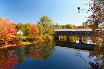 Obraz premium Covered bridge over the river as a feature of American architecture. Autumn river landscape and old bridge.