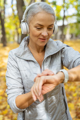 Mature pleasant woman checking her pulse outside