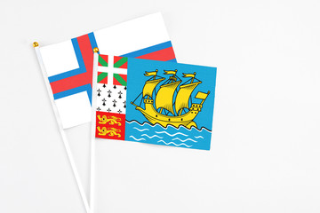 Saint Pierre And Miquelon and Faroe Islands stick flags on white background. High quality fabric, miniature national flag. Peaceful global concept.White floor for copy space.