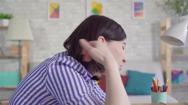 Young woman sitting at a laptop feels a pain in the neck and back due to stooping