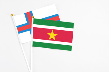 Suriname and Faroe Islands stick flags on white background. High quality fabric, miniature national flag. Peaceful global concept.White floor for copy space.